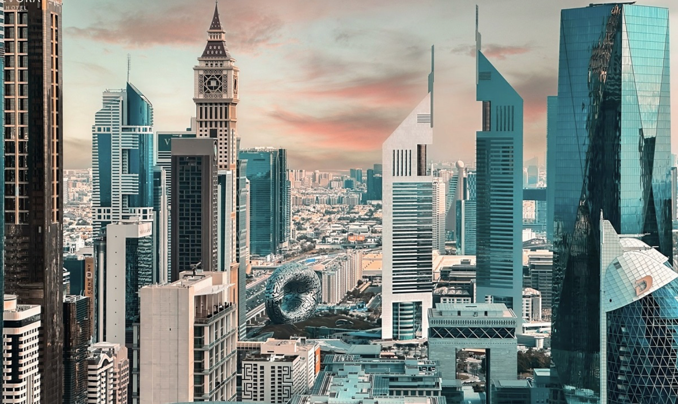 Panoramic view of Dubai’s Sheikh Zayed Road skyline featuring the Museum of the Future, Emirates Towers and surrounding commercial high-rises at sunset.