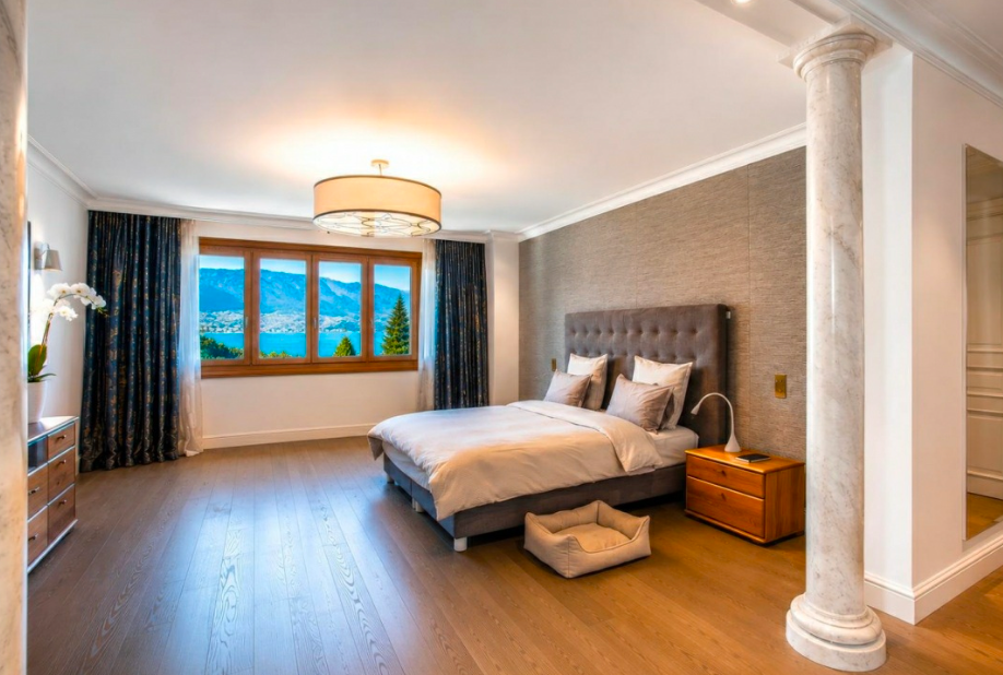 Elegant bedroom suite with uninterrupted Lake Geneva views and floor-to-ceiling windows overlooking the waterfront.