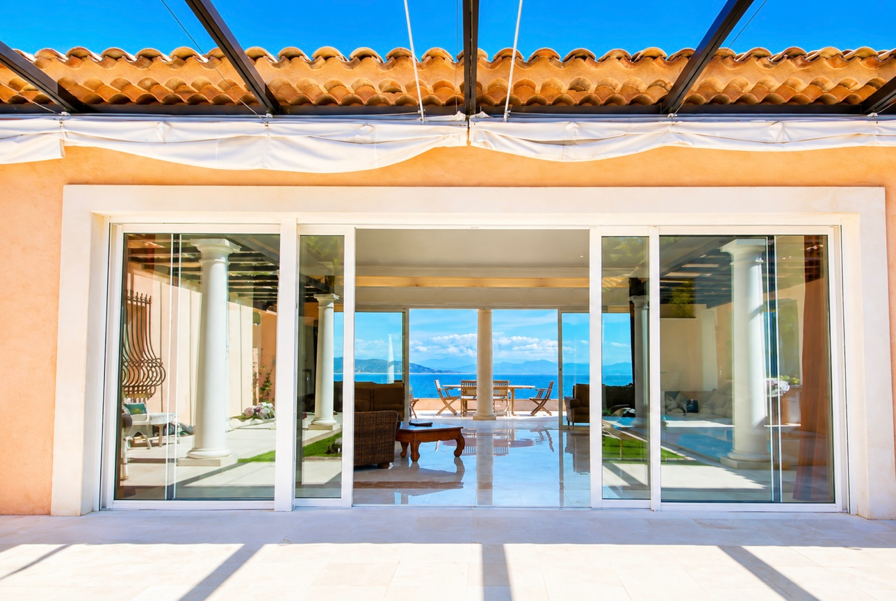 Luxury balcony terrace with reflective sea views and soft Riviera sunset lighting overlooking the coastline.