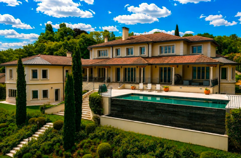Front elevation of a luxury Lake Geneva waterfront estate with landscaped gardens and direct lakefront positioning.