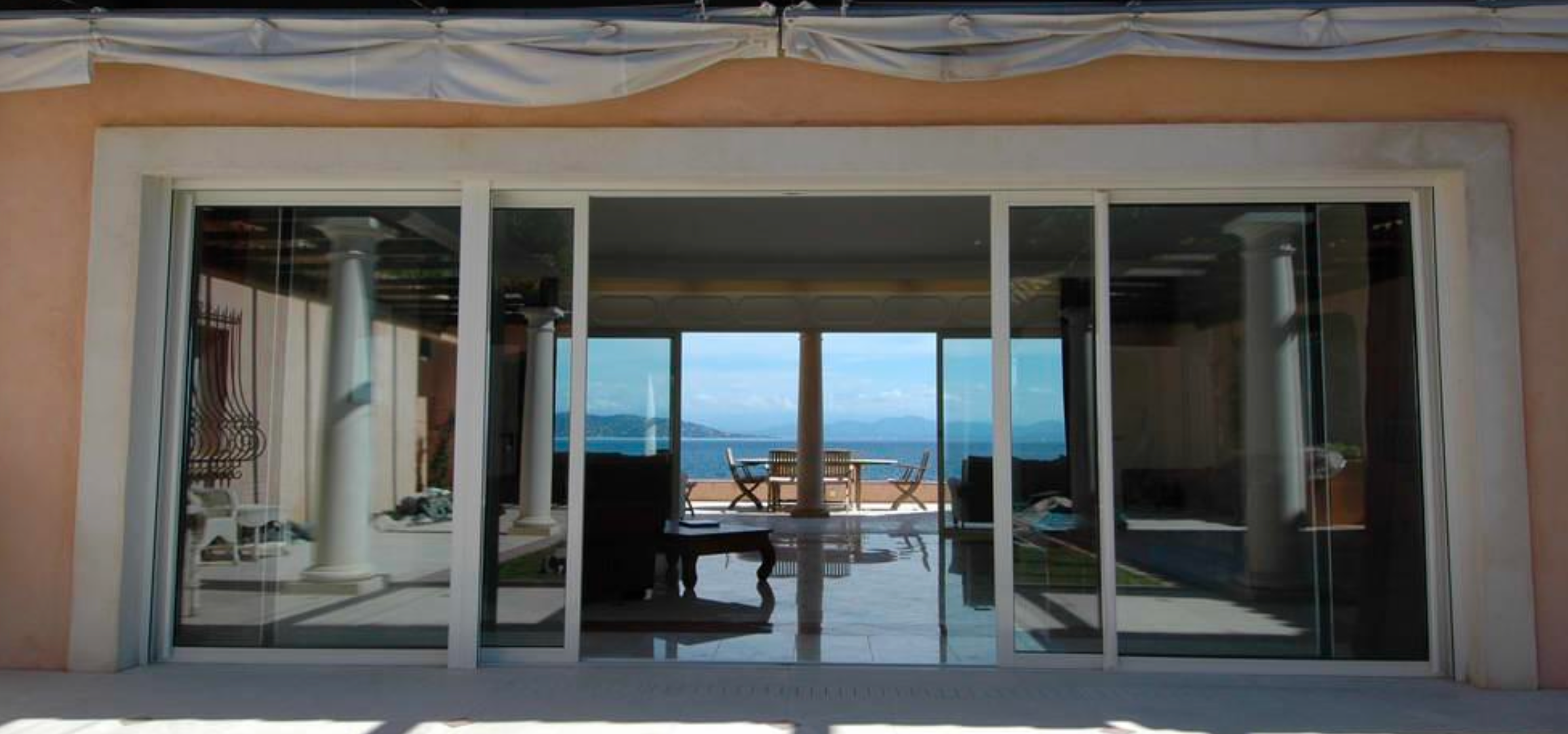 Luxury balcony terrace with reflective sea views and soft Riviera sunset lighting overlooking the coastline.